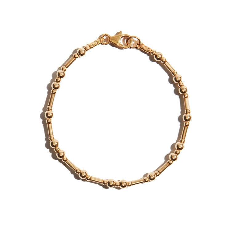 The photo of our Gold and Ball Bracelet features alternating strung beads and textured tube beads, creating a delicate & simple gold bracelet that everyone will love.