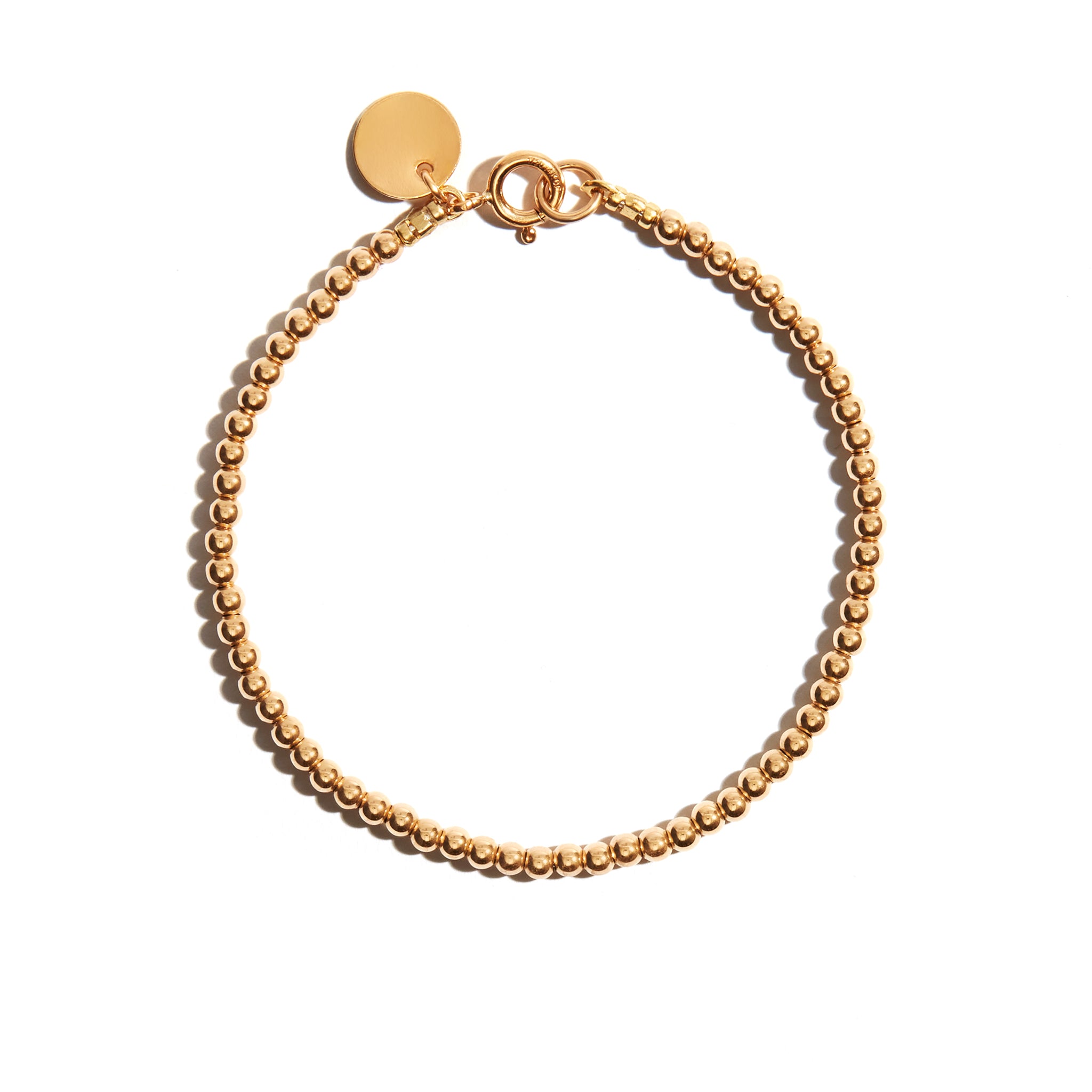 Photo of our Delicate Stacking Bracelet is a simple style with small, delicate gold beads and a gold coin charm at the clasp. It is a classic, simple style making it an elegant and feminine choice when worn alone, but is also a perfect base for stacking.