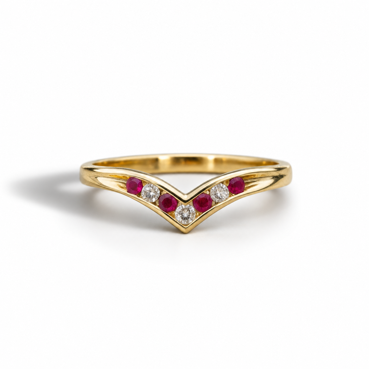 A yellow gold V-shaped ring featuring a central diamond and flanked by two rows of small red and clear gemstones, set against a clean white background.