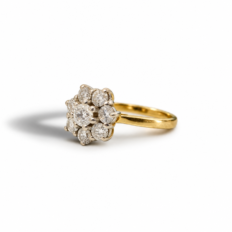 A yellow gold ring featuring a cluster of round-cut diamonds, photographed on a clean white background with a soft shadow.