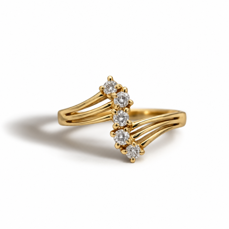 A beautifully distinctive vintage ring in 9ct gold, set with a graduated line of sparkling diamonds in an elegant open crossover design. Delicate yet striking, the flowing gold bands create a soft sculptural shape that gives the piece a refined, timeless feel.

Its constellation-inspired arrangement of diamonds catches the light beautifully, adding subtle brilliance and making this ring perfect for both everyday wear and special occasions. A characterful vintage piece with classic charm and a slightly celes