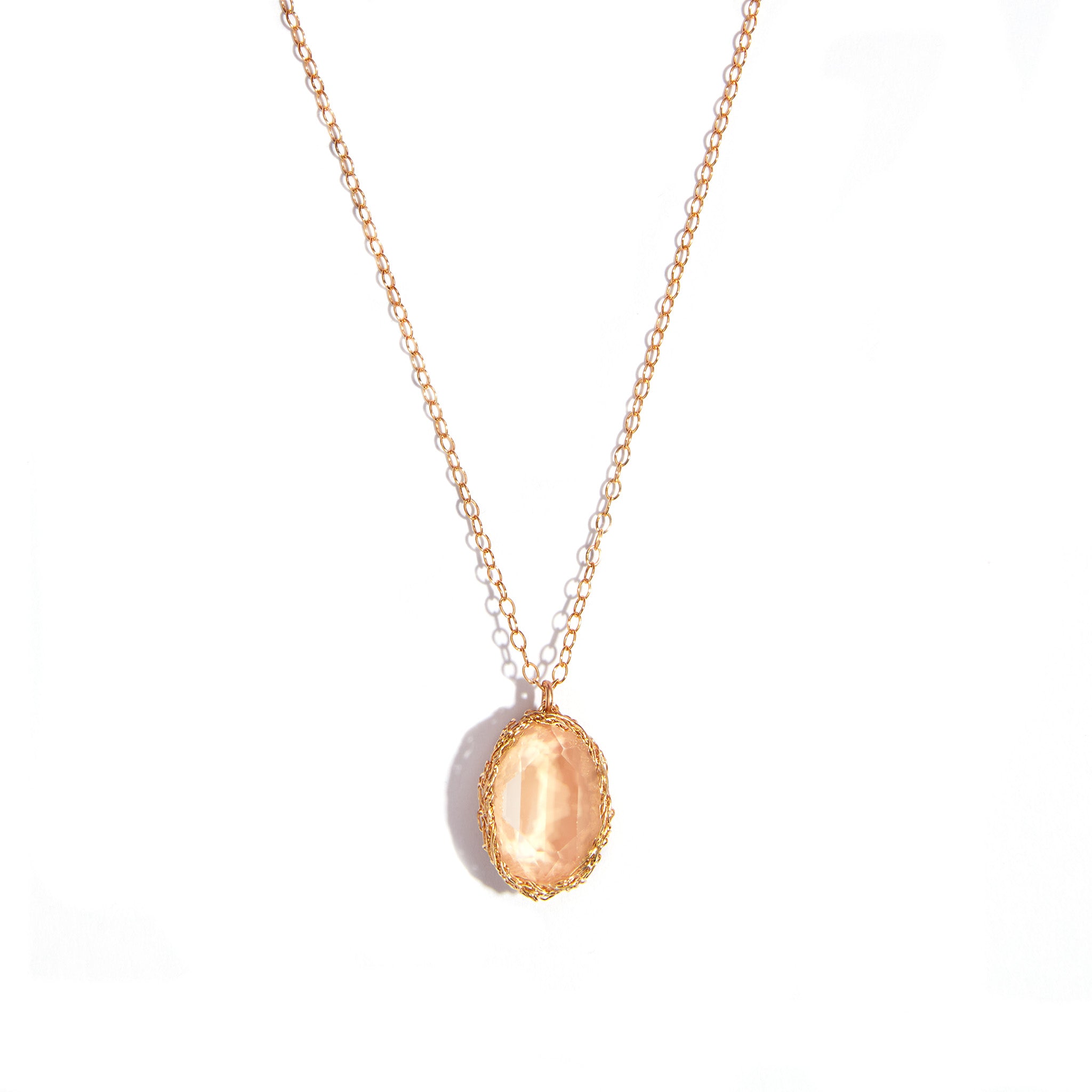 Close-up image of a crochet pendant featuring a sand opal stone, set in 14 carat gold-filled material. This stylish accessory adds elegance to any look.