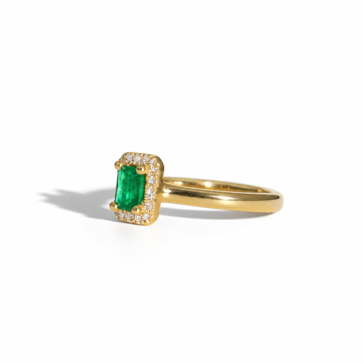 Yellow gold emerald and diamond halo ring with rectangular emerald-cut green gemstone