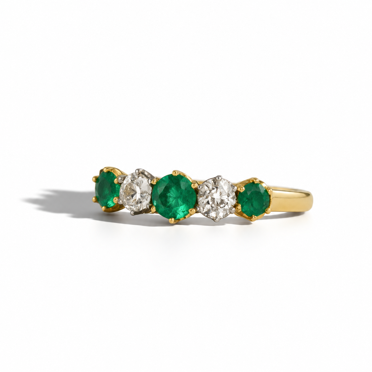 Yellow gold five-stone emerald and diamond ring featuring three round emeralds and two round brilliant-cut diamonds