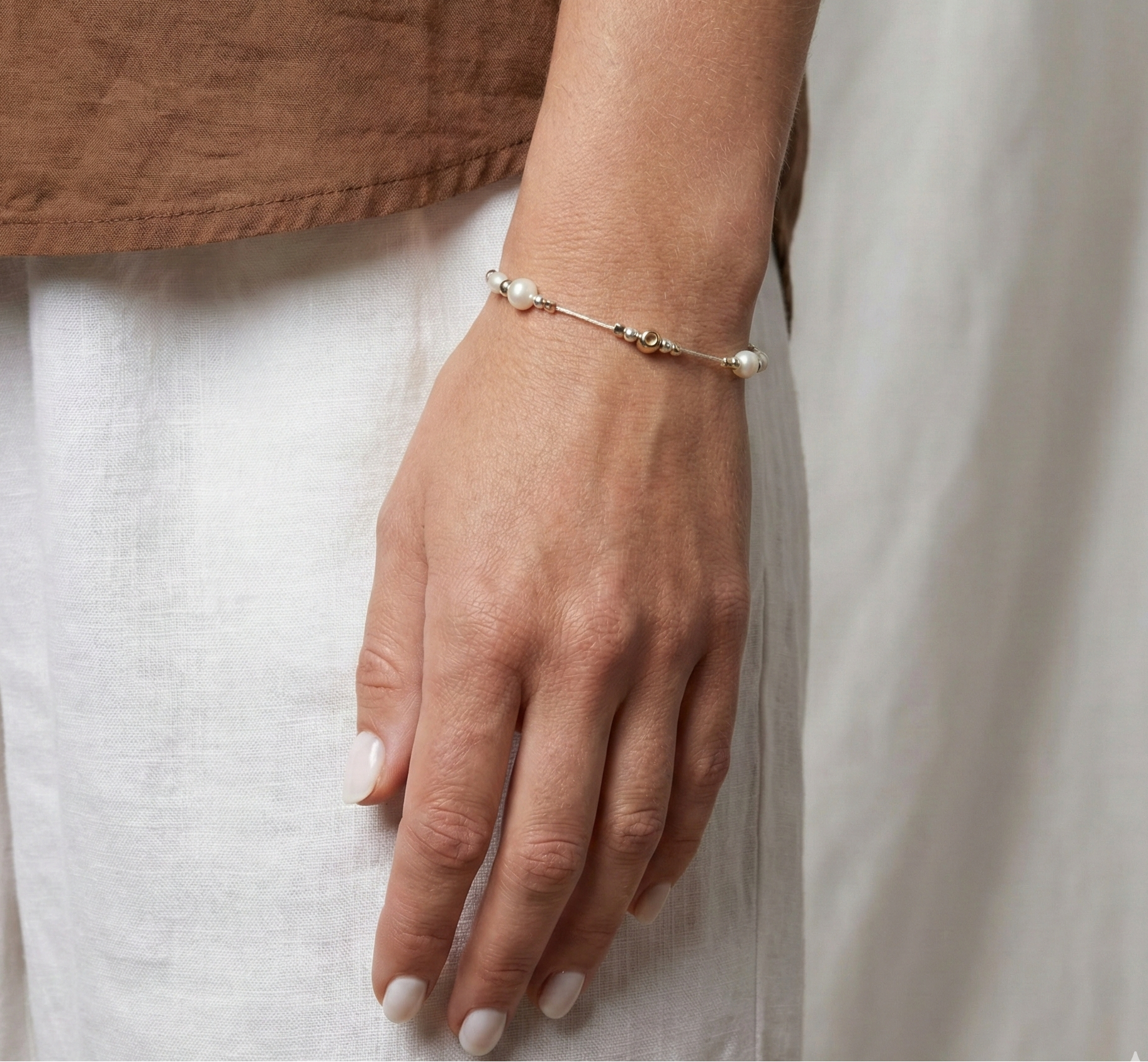 Hand wearing a delicate bracelet on a neutral background