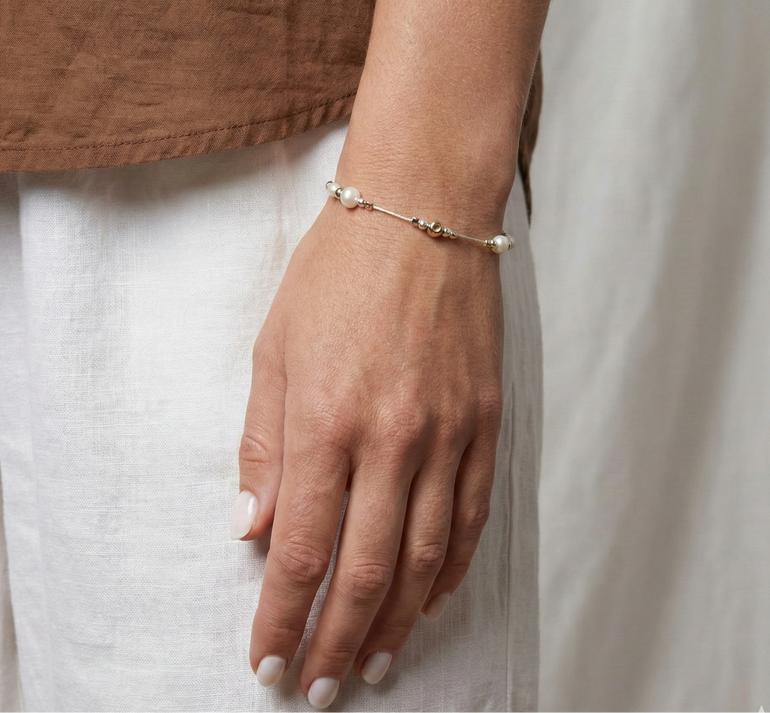 Hand wearing a delicate bracelet on a neutral background