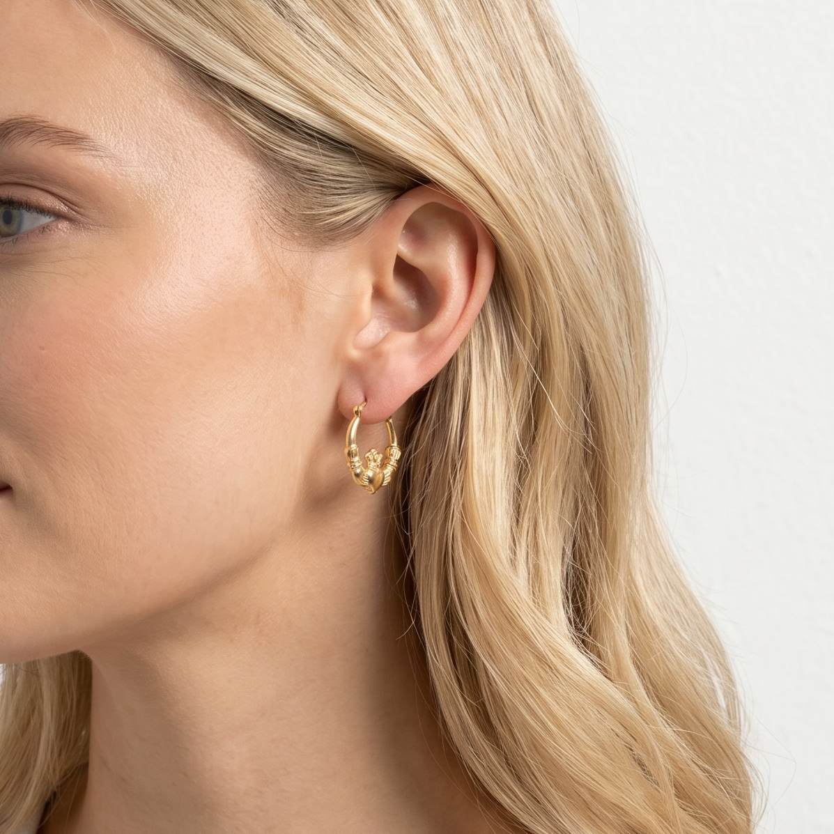 Woman wearing gold hoop earrings against a plain background