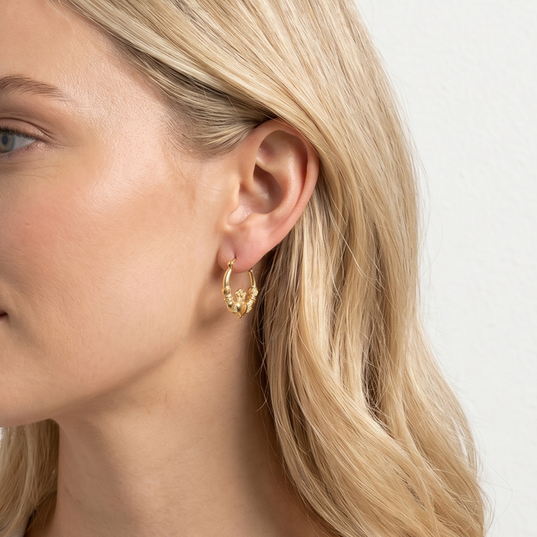 Woman wearing gold hoop earrings against a plain background