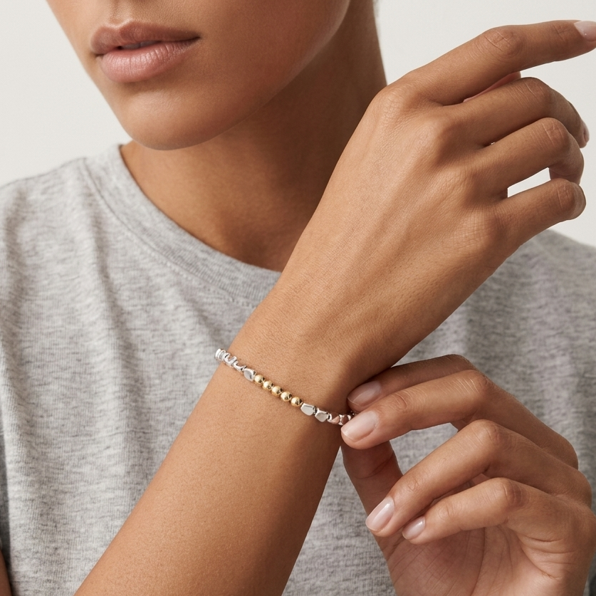 Person wearing a silver bracelet on a neutral background