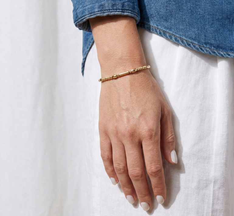 Hand wearing a gold bracelet on a white background