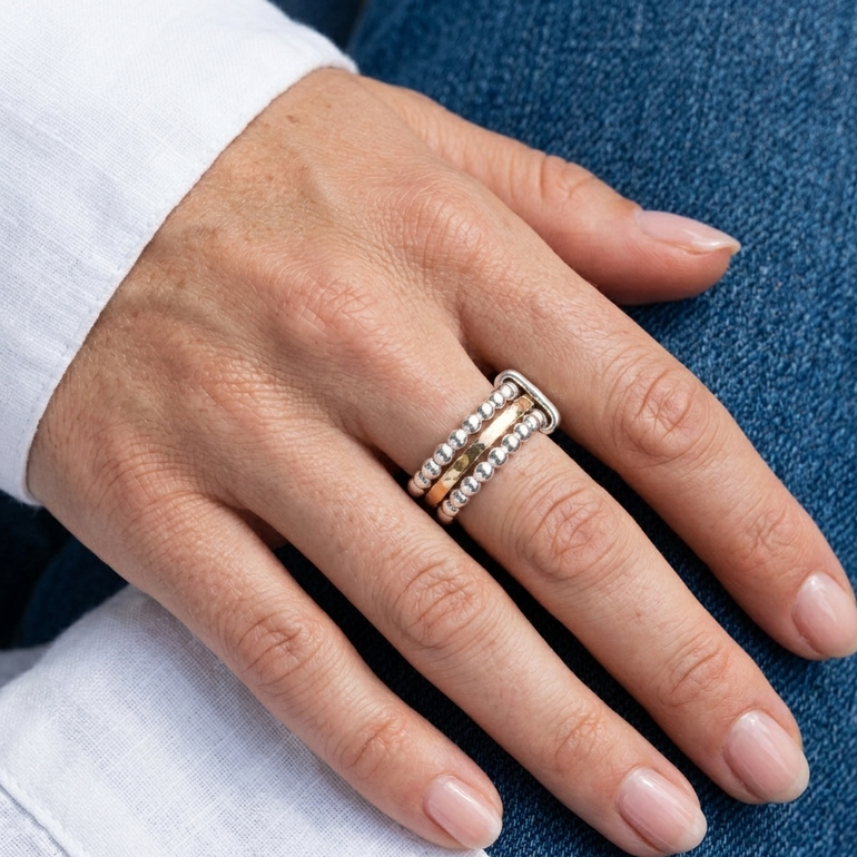 Hand wearing a stack of rings on a blue background
