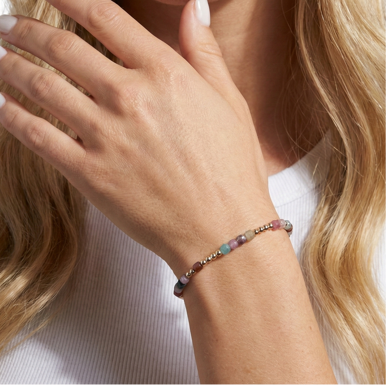 Close-up of a woman's hand wearing a beaded bracelet with a blurred background