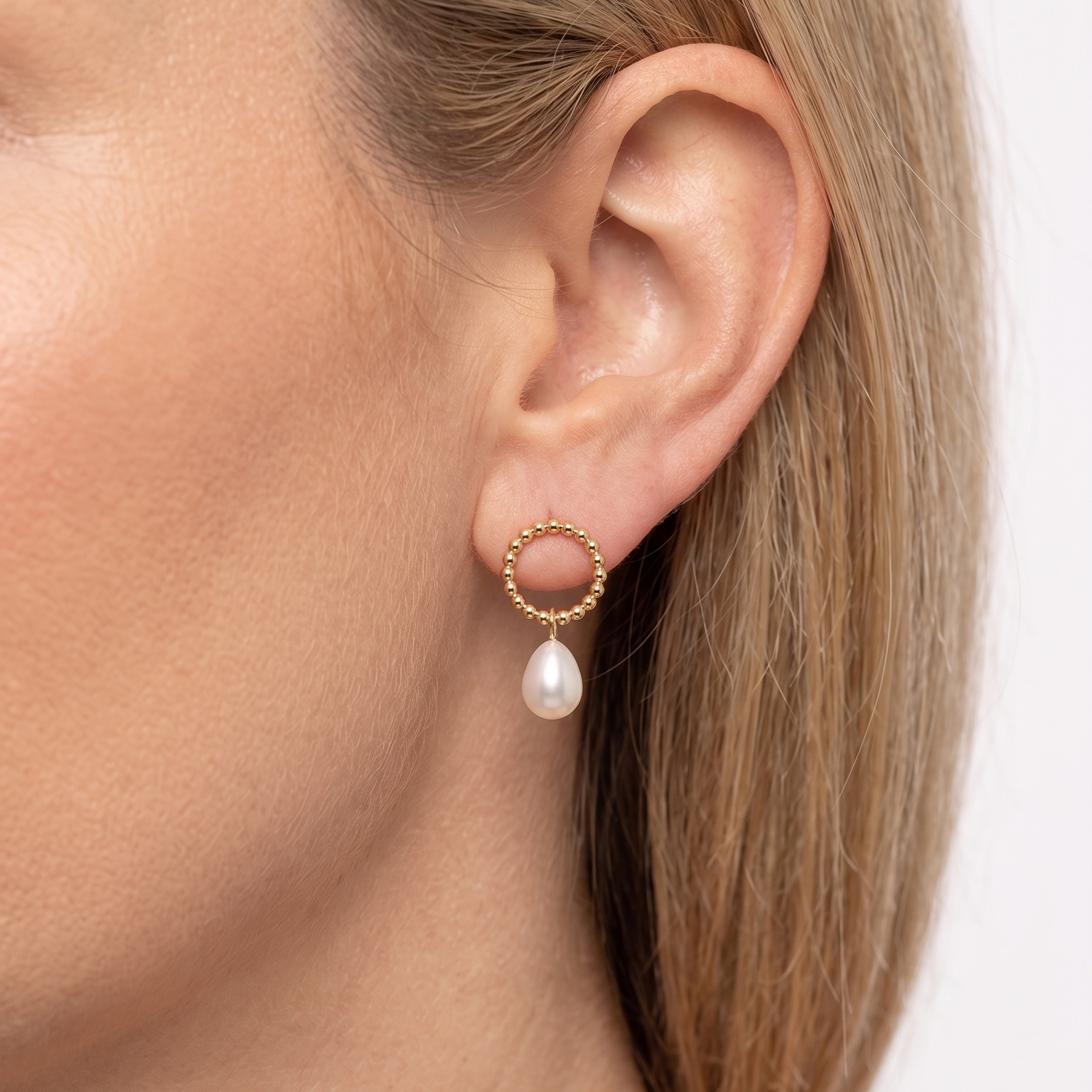 Gold hoop earring with a pearl on a white background