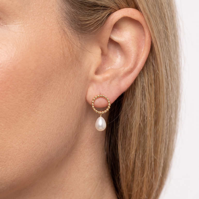 Gold hoop earring with a pearl on a white background