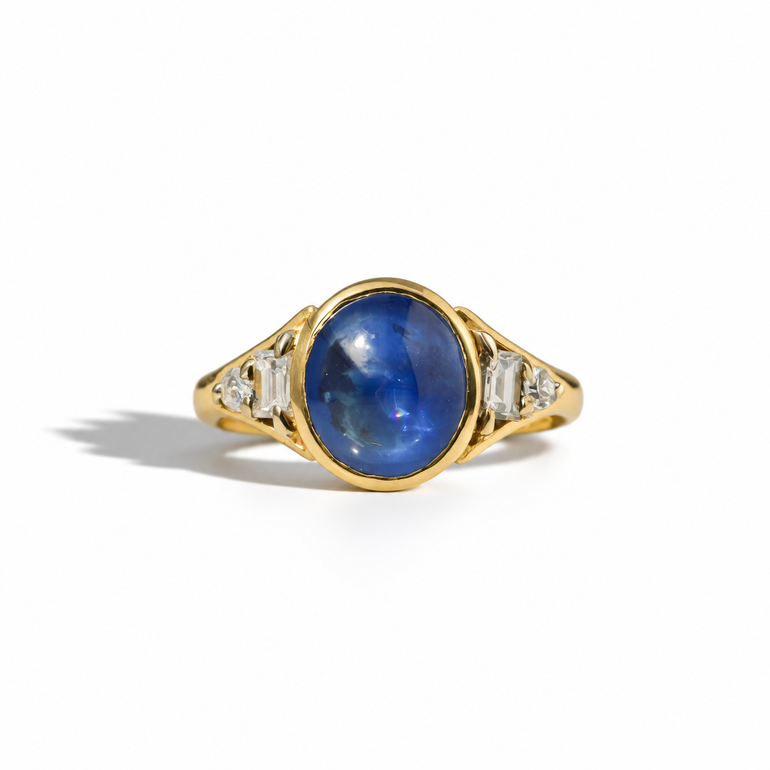 Vintage yellow gold ring with oval blue sapphire cabochon and diamond-set shoulders