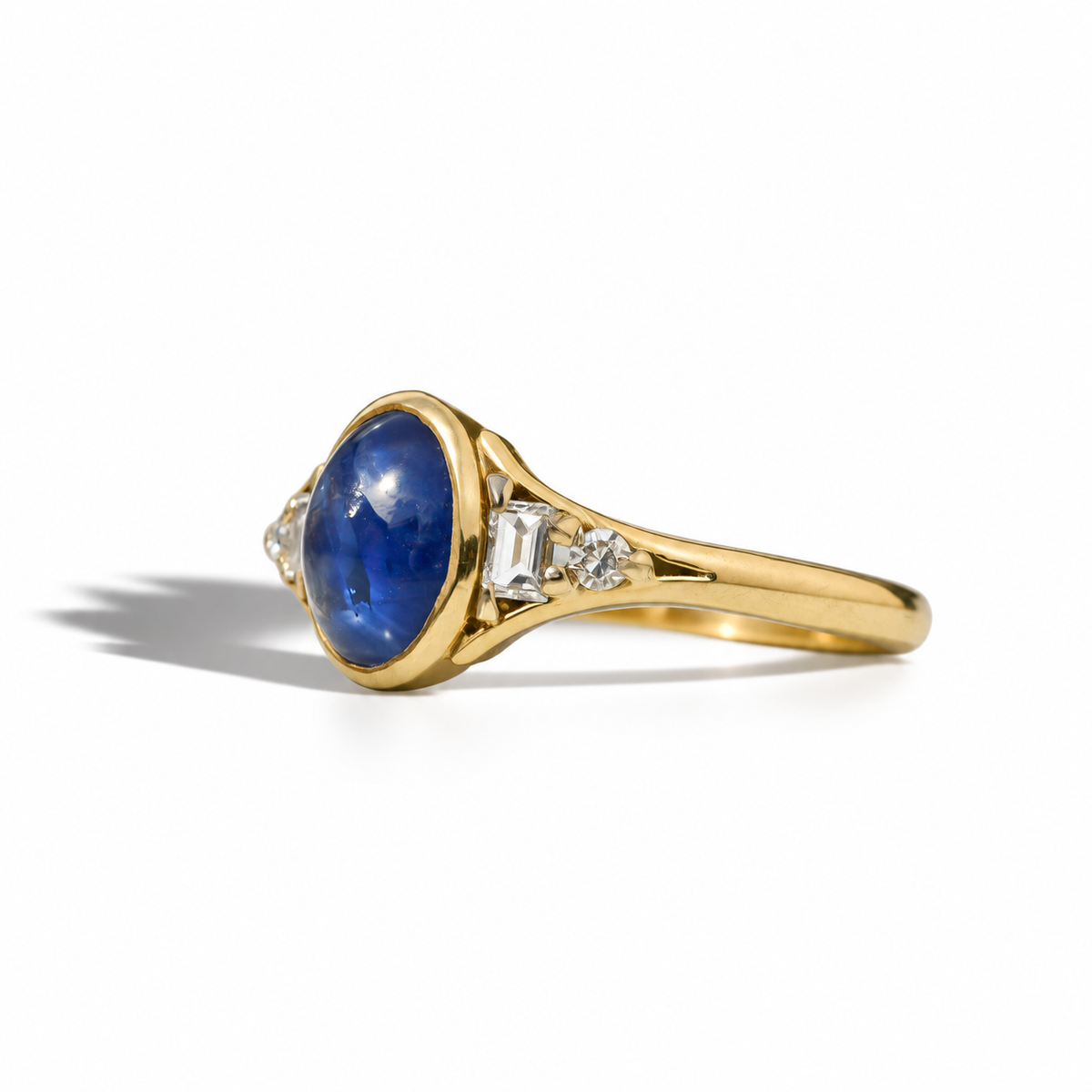 Vintage yellow gold ring with oval blue sapphire cabochon and diamond-set shoulders