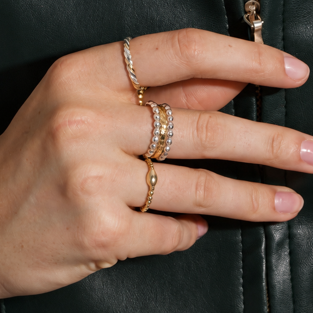 Woman wearing layered Méaróg 14ct gold fill rings styled with a dark leather jacket.