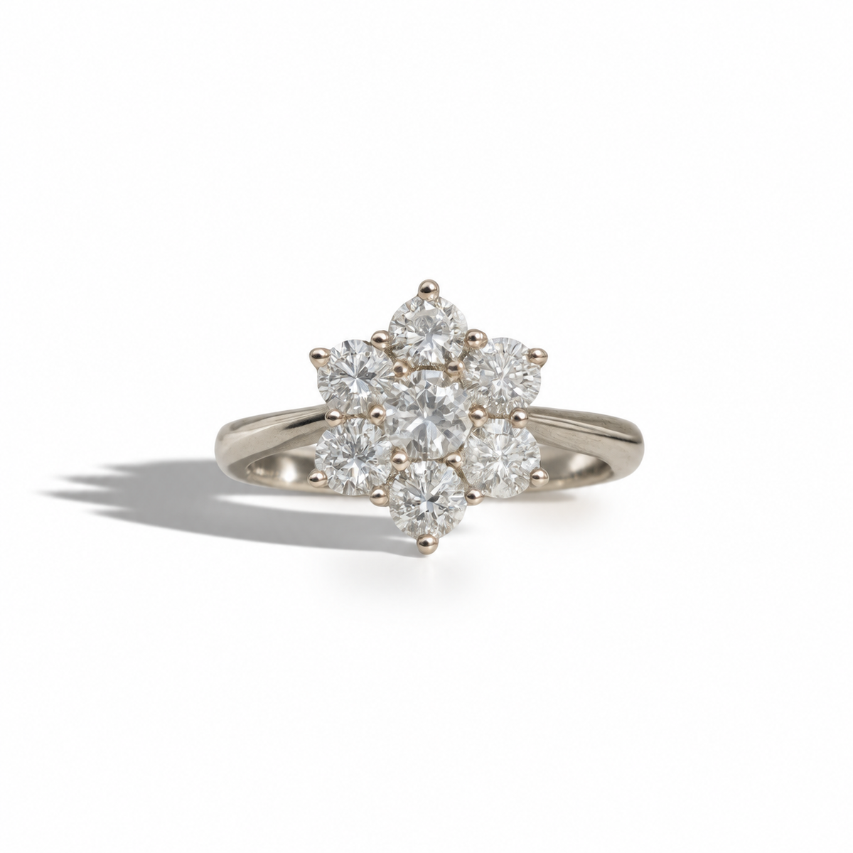 Vintage white gold diamond cluster ring featuring a central round brilliant diamond surrounded by six round diamonds in a floral setting.