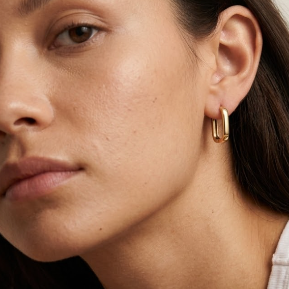 Close-up of a person wearing a gold hoop earring.