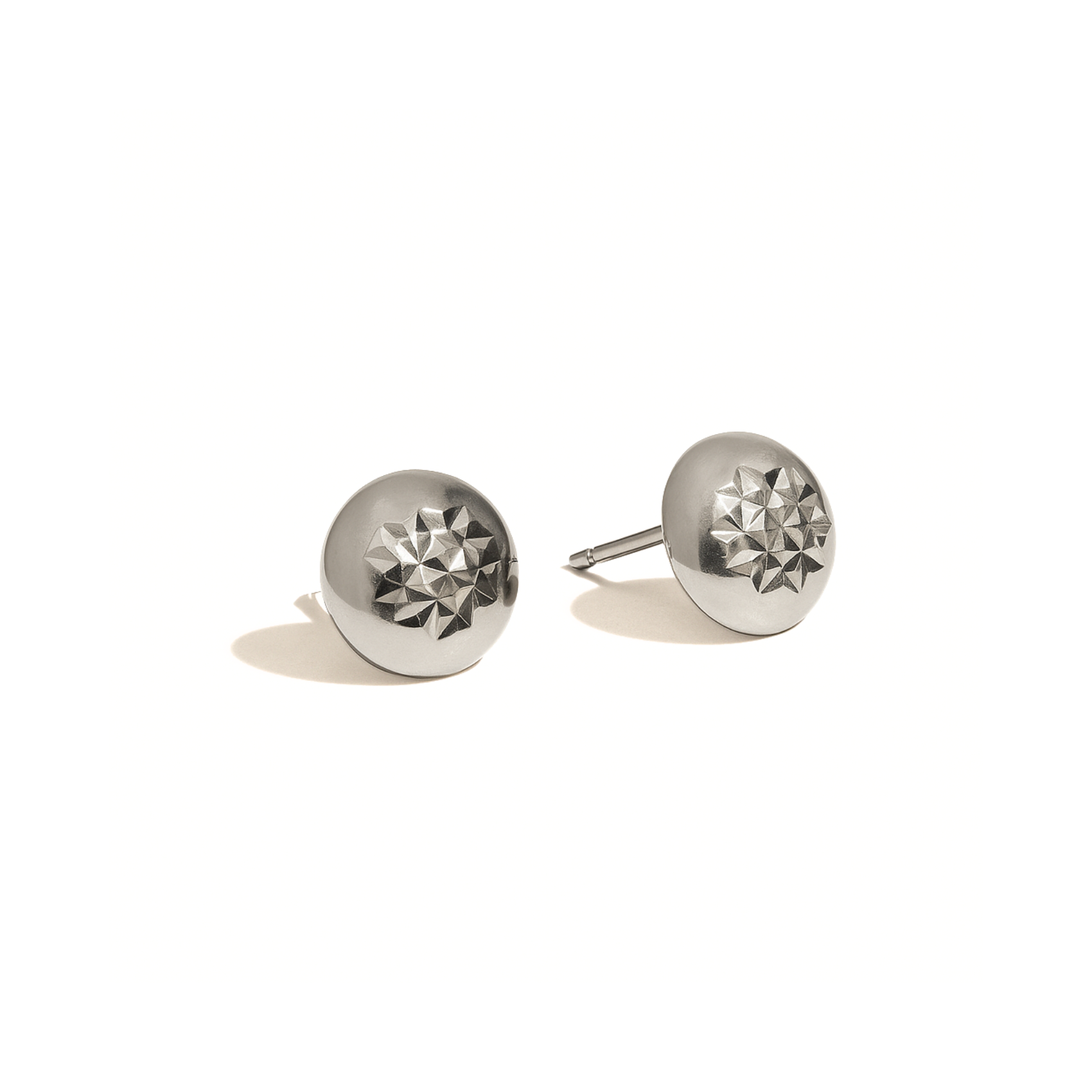 Pair of silver round earrings with geometric design on a white background