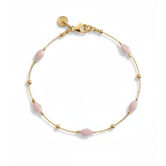 Gold bracelet with pink beads on a white background