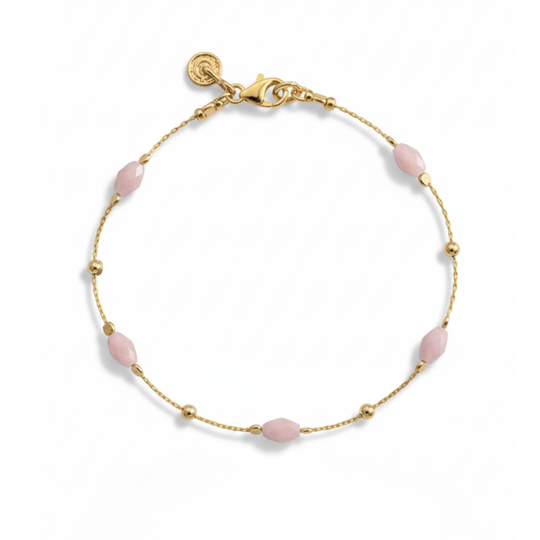 Gold bracelet with pink beads on a white background