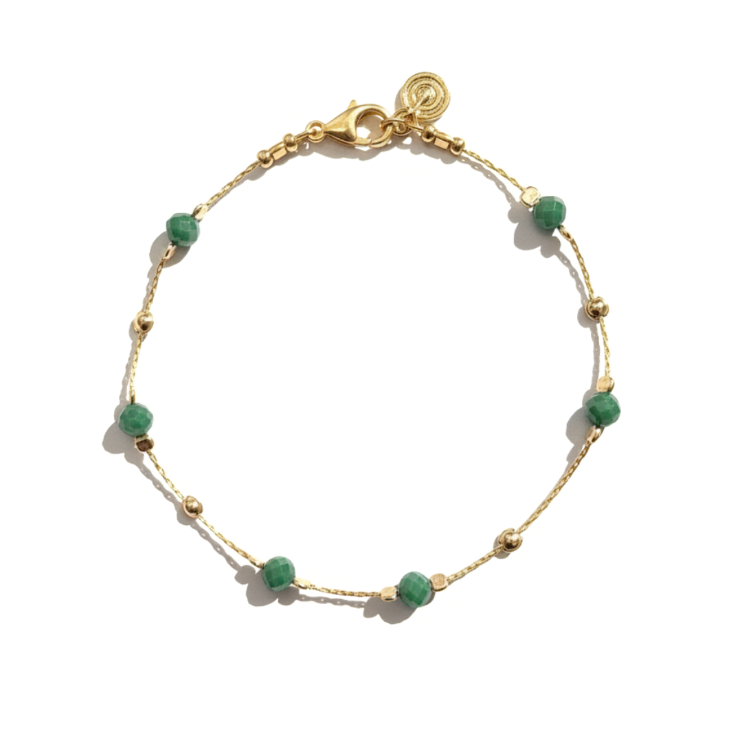 Gold bracelet with green beads on a white background