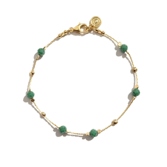 Gold bracelet with green beads on a white background