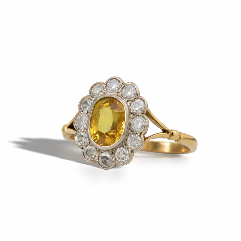 Vintage yellow gold ring with an oval golden-yellow gemstone, surrounded by a scalloped halo of round diamonds in a white metal setting.