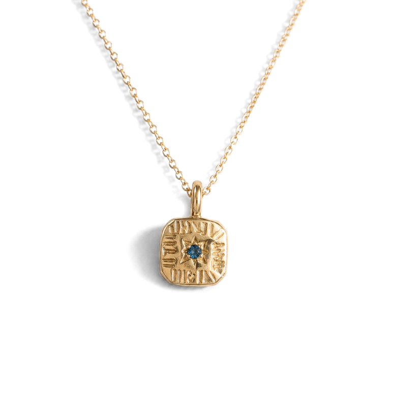 A gold chain necklace with a square engraved pendant featuring a small blue stone in the center, shown against a plain white background.