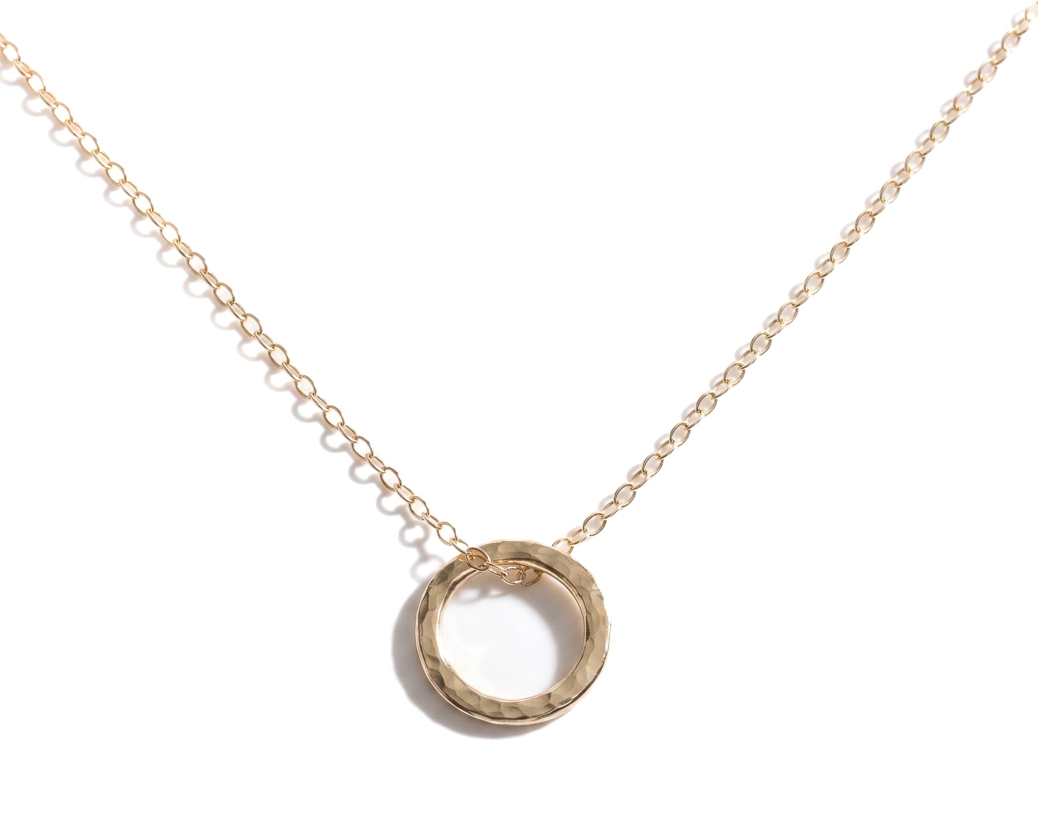 Gold necklace with a circular pendant on a white background