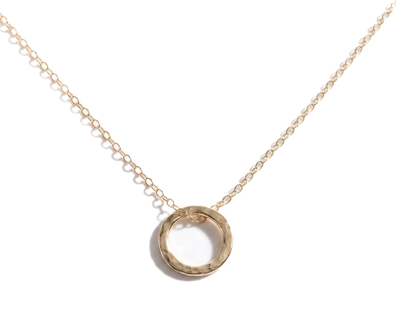 Gold necklace with a circular pendant on a white background