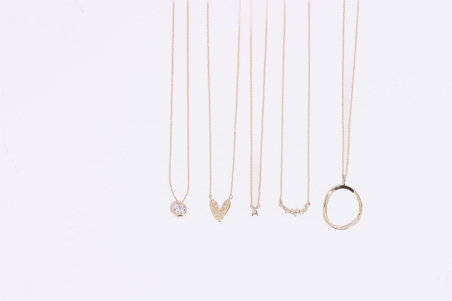 Set of gold necklaces with various pendants on a white background