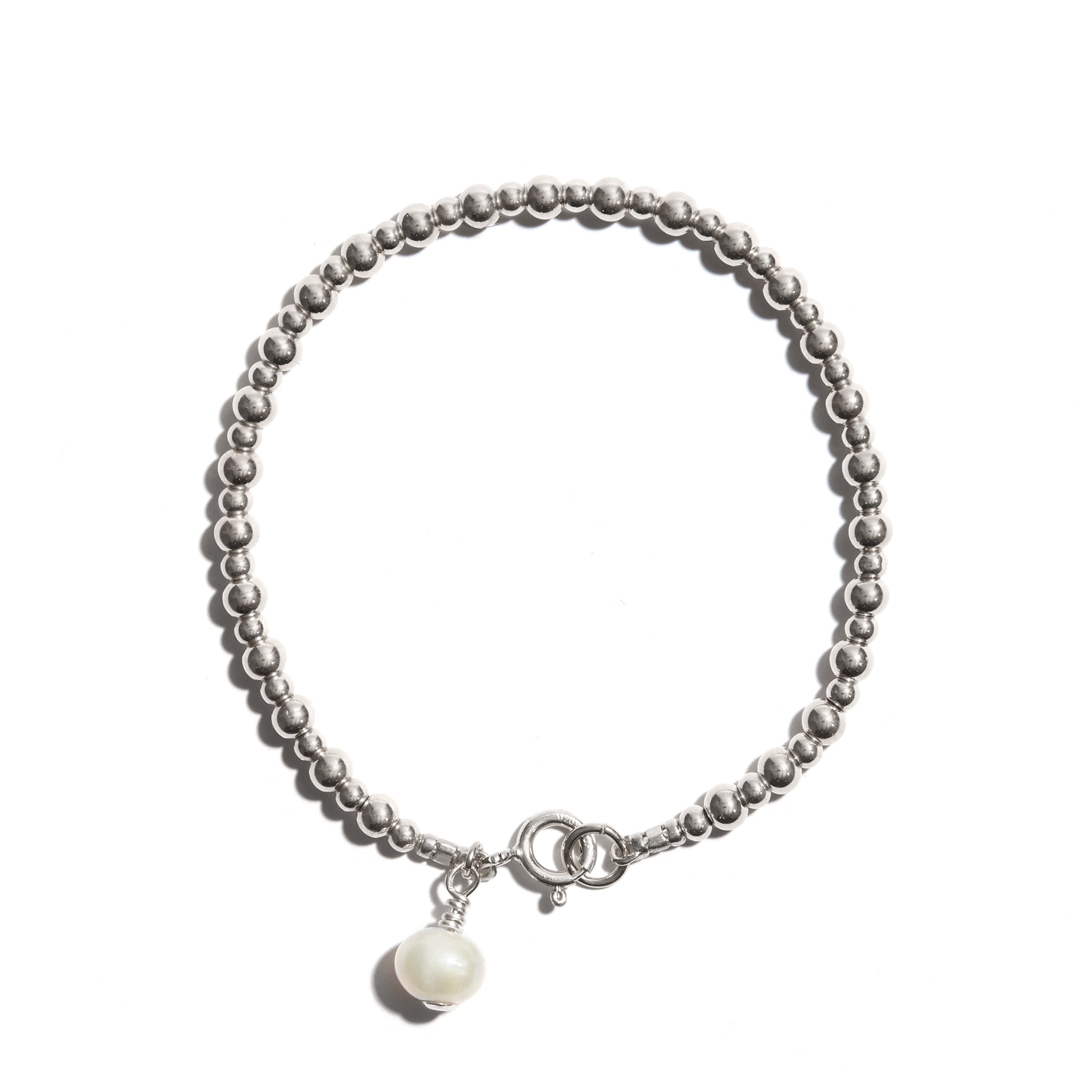 Photo of our Pearl Charm Stacking Bracelet features larger followed by smaller beads consecutively strung, and a single pearl charm at the clasp to add just a little extra bit of elegance.