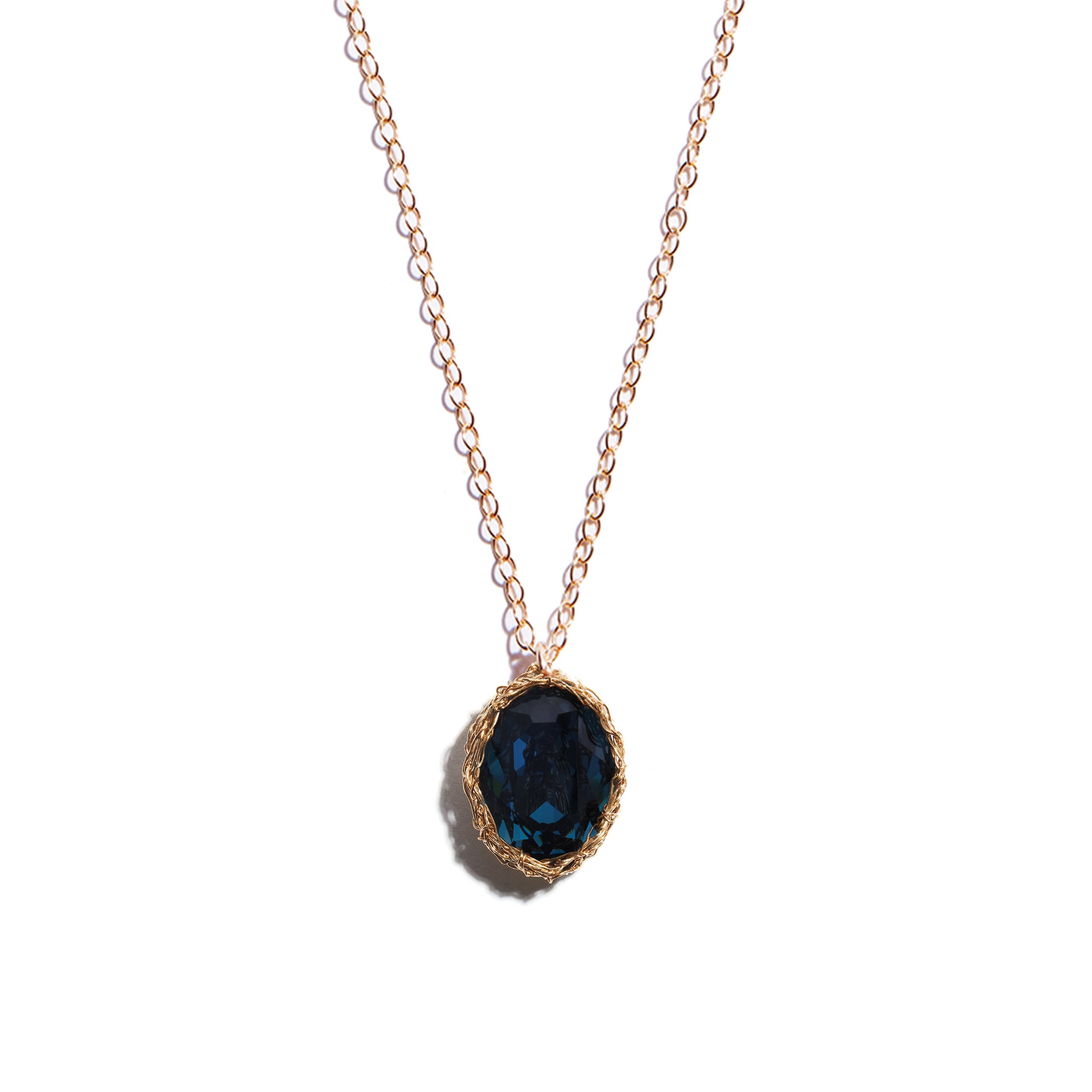 Close-up photo of a deep blue oval pendant crafted from 14 carat gold-filled metal. This sophisticated accessoty adds a touch of luxury to any attire.