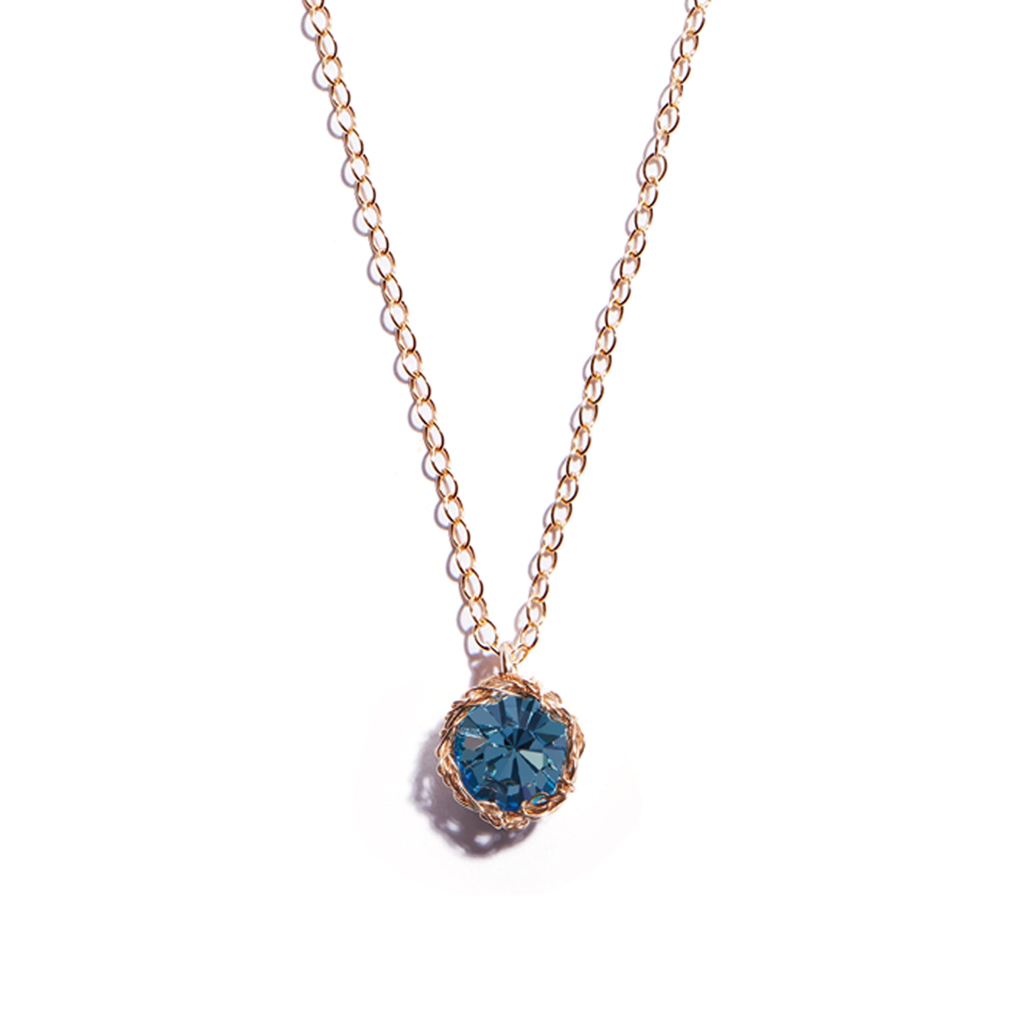Close-up photo of a crochet necklace featuring a March birthstone pendant made of aquamarine, set in 14 ct gold-filled metal.