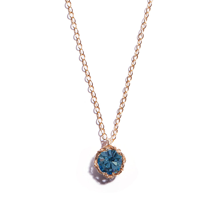 Close-up photo of a crochet necklace featuring a March birthstone pendant made of aquamarine, set in 14 ct gold-filled metal.