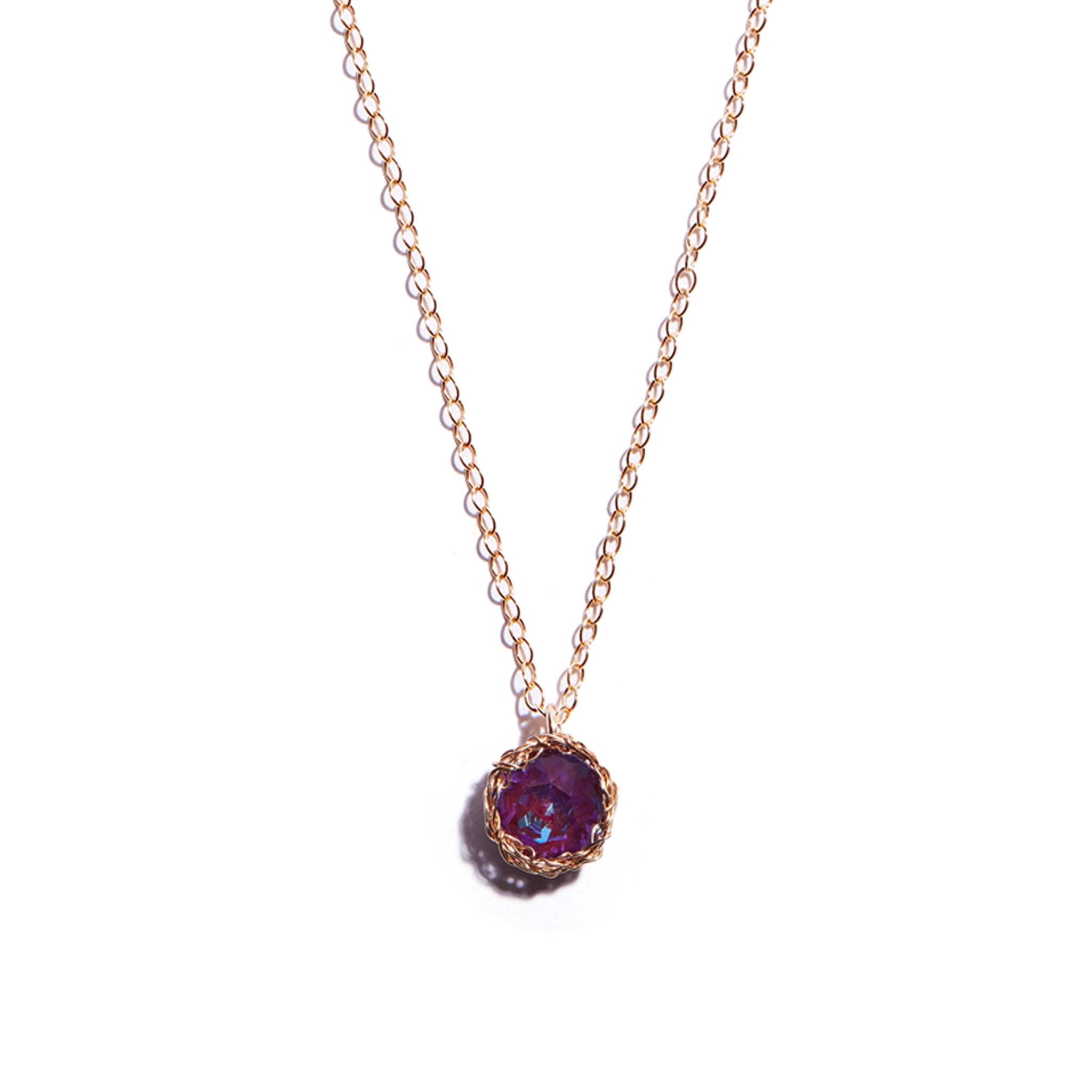 Close-up photo of a crochet necklace featuring a January birthstone pendant made or garnet, set in 14 ct gold-filled  metal.