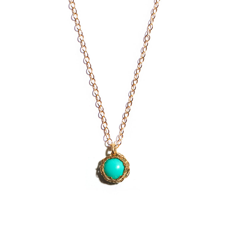 Close-up photo of a crochet necklace featuring a December birthstone pendant made of turquoise, set in 14 ct gold-filled metal.