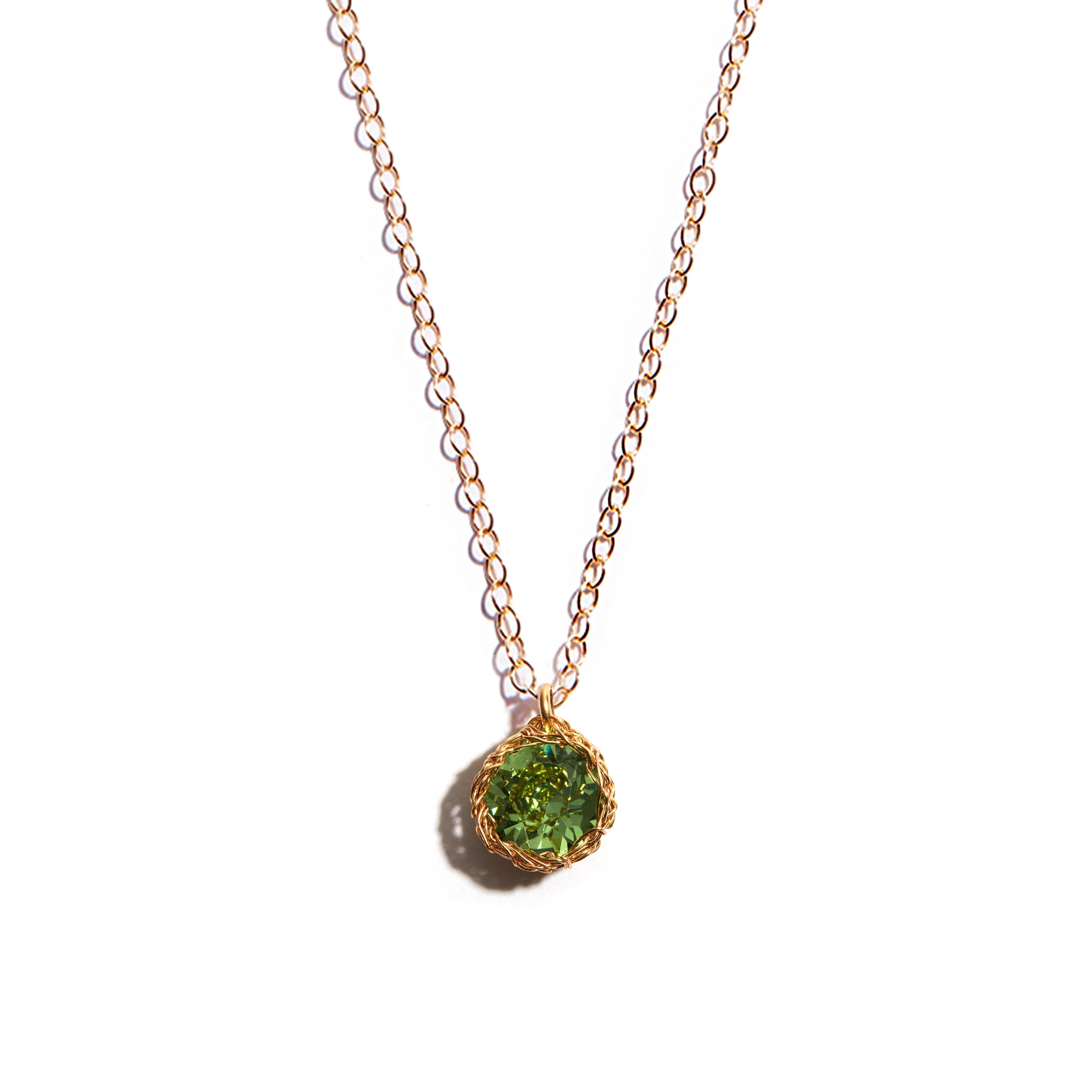 Close-up photo of a crochet necklace featuring a August birthstone pendant made of peridot, set in 14 ct gold-filled metal.