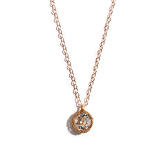 Close-up photo of a crochet necklace featuring a April birthstone pendant made of crystal quartz, set in 14 ct gold-filled metal.