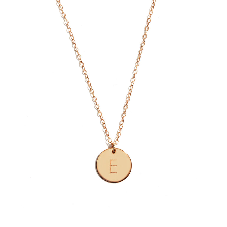 Close-up photo of a personalized initial disc pendant in 14 carat gold-fill, showcasing elegant engraving.