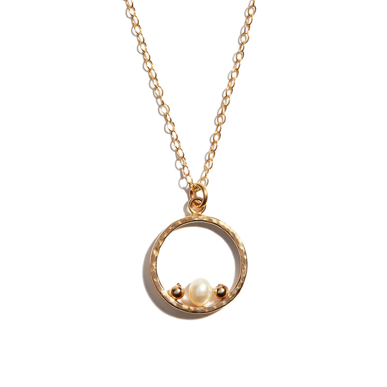 Photo of a luxurious open circle pearl necklace crafted from high-quality 14 carat gold-fill. The delicate pearls are elegantly arranged within the circular pendant, exuding timeless sophistication and charm.